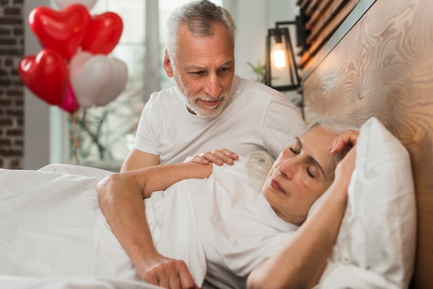 Senior hombre sorprendente esposa en la cama