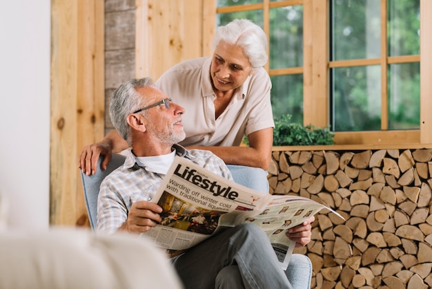 Senior hombre sosteniendo el periódico en la mano mirando a su esposa