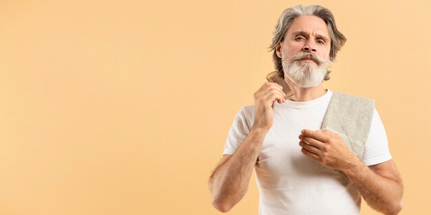 Senior hombre con toalla peinándose la barba