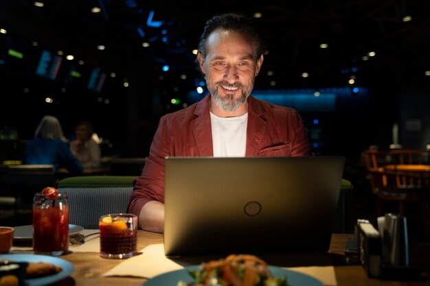 Senior hombre trabajando en su computadora portátil en un restaurante