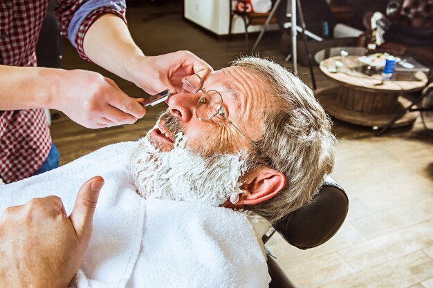 Senior hombre visitando estilista en peluquería.