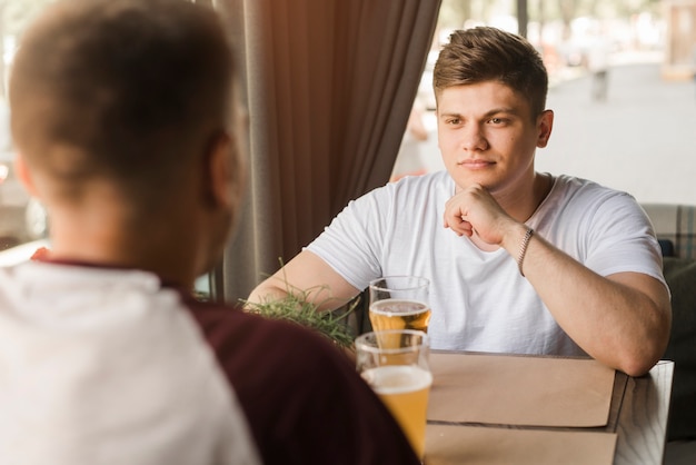 Senior joven sentado con su amigo en el restaurante