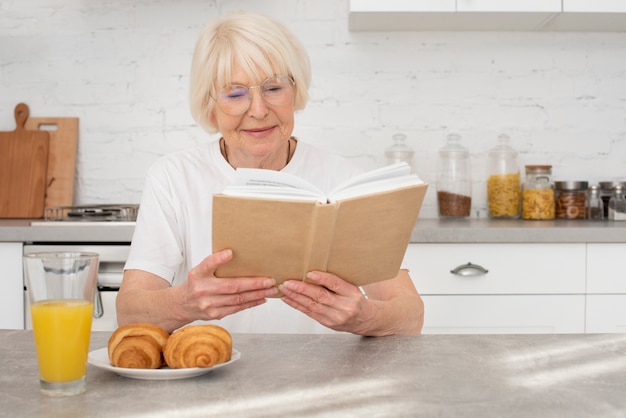 Foto gratuita senior leyendo un libro en la cocina