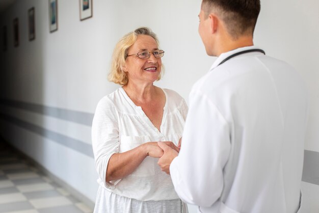 Senior mujer cogidos de la mano del médico