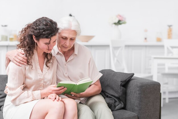 Senior mujer e hija leyendo libros juntos en casa