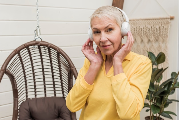 Foto gratuita senior mujer escuchando música aunque auriculares blancos