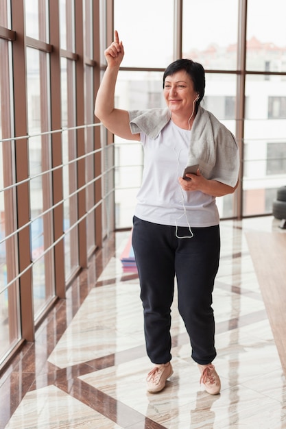 Senior mujer escuchando música en el gimnasio