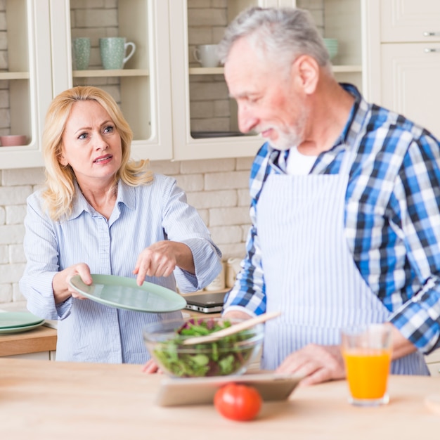 Senior mujer gritando a su esposo por limpiar el plato