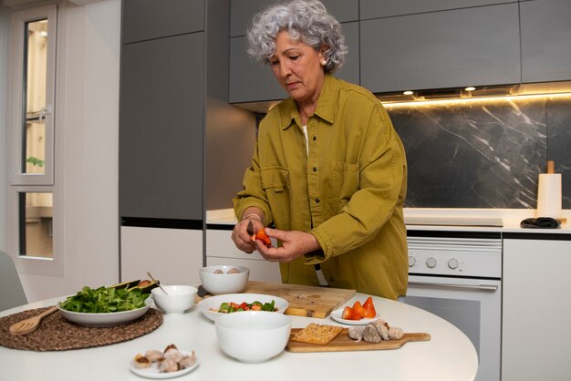 Senior mujer haciendo plato con higos en la cocina