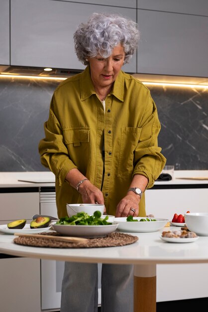 Senior mujer haciendo plato con higos en la cocina