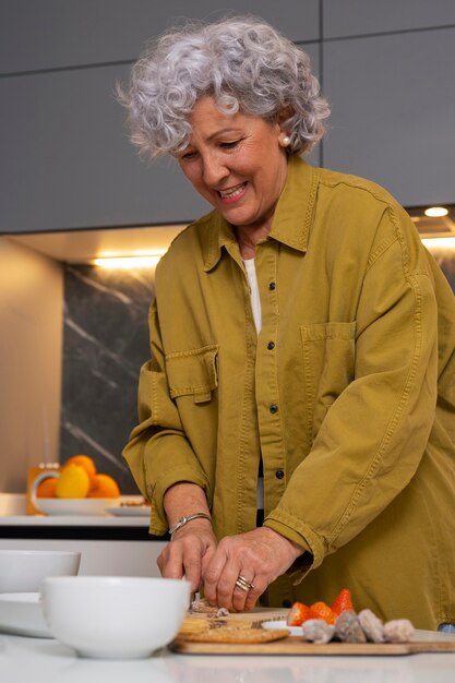 Senior mujer haciendo plato con higos en la cocina