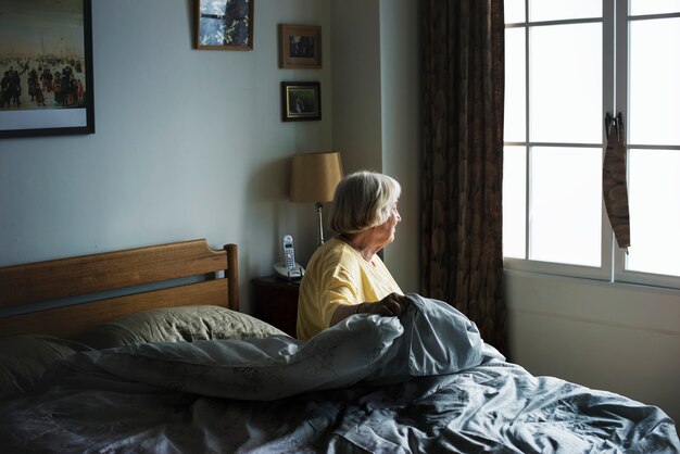 Senior mujer sentada en un dormitorio
