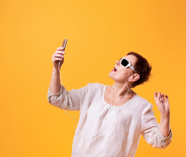 Foto gratuita senior mujer tomando selfies sobre fondo amarillo