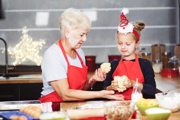 Senior con niña amasando masa en la cocina