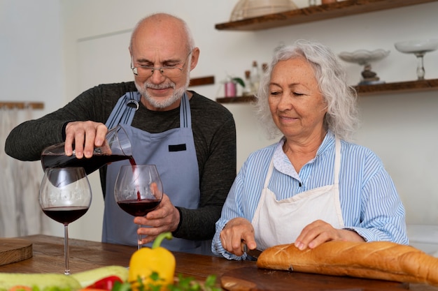 Foto gratuita senior pareja cocinando juntos en la cocina y tomando vino