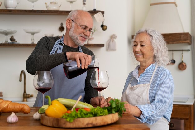 Senior pareja cocinando juntos en la cocina y tomando vino