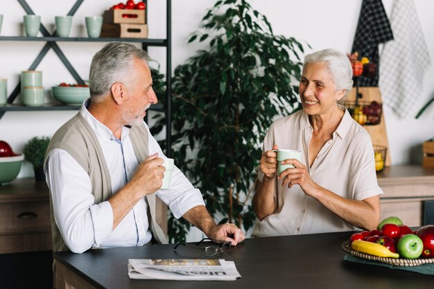 Senior pareja sentada en la cocina disfrutando del café