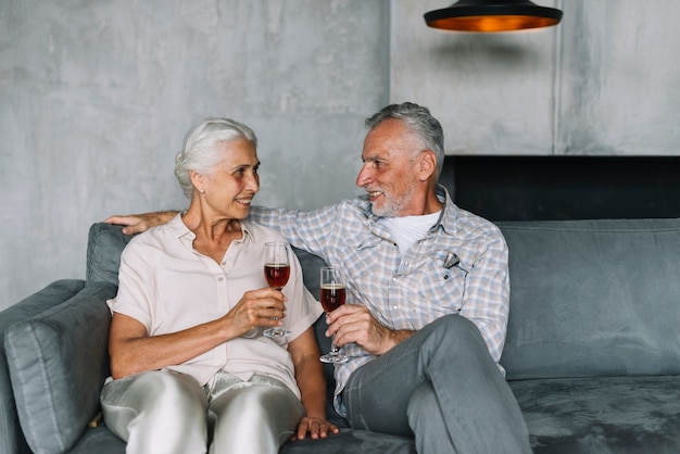 Foto gratuita senior pareja sentada en el sofá con copa de vino