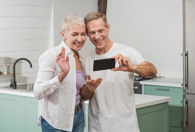 Senior pareja tomando un selfie en la cocina