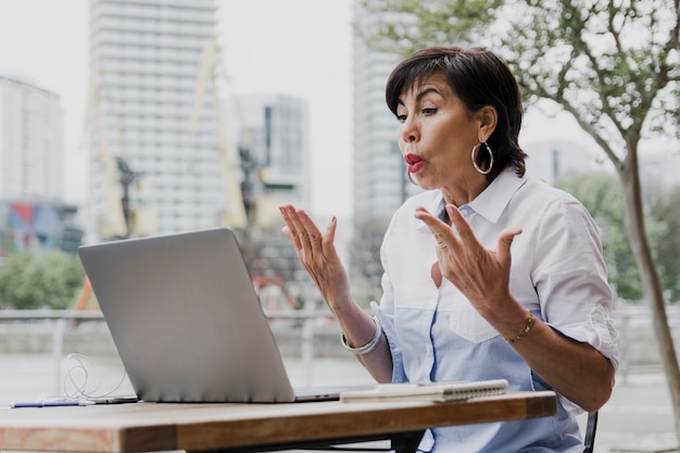 Senior sentado al aire libre con laptop