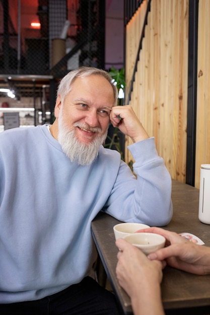 Foto gratuita senior sonriente hombre sentado en la mesa