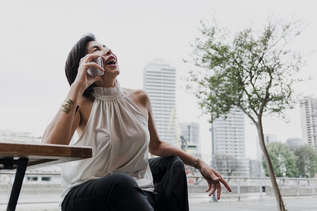 Foto gratuita senior sosteniendo un teléfono en el fondo de la ciudad