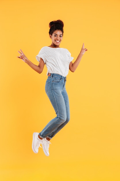 Señora alegre africana divertida saltando y sonriendo aislado