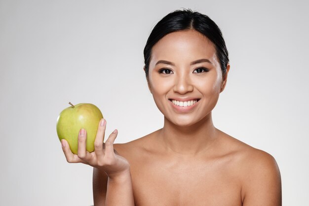 Señora alegre sonriendo y comiendo manzana verde