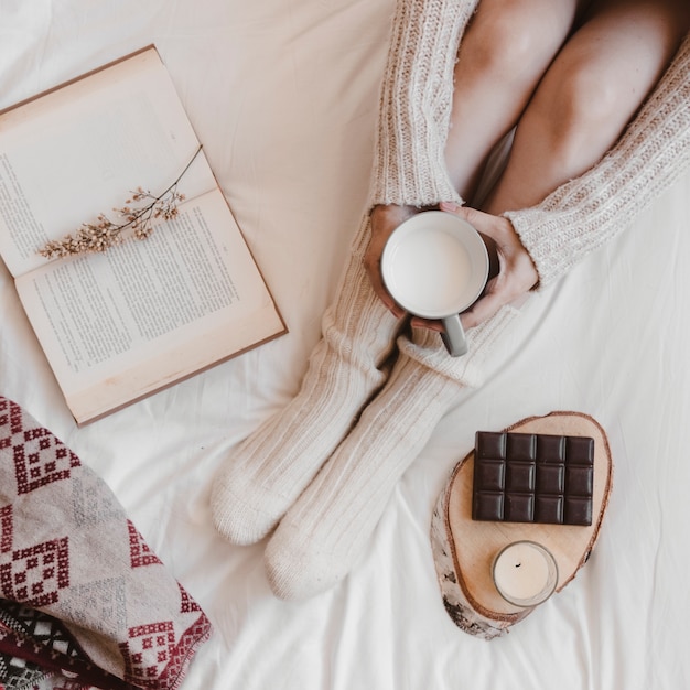 Señora anónima con leche cerca de libro y chocolate