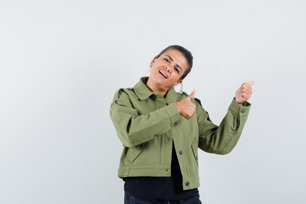 Señora apuntando a un lado con los pulgares hacia arriba en la chaqueta