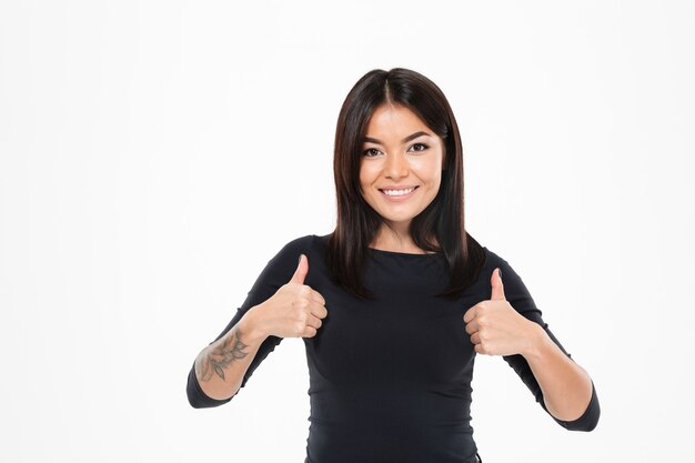 Señora asiática joven feliz que muestra los pulgares para arriba.