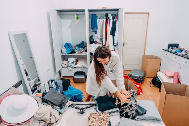 Señora de aspecto agradable dentro de la habitación moderna del apartamento prepararse para el viaje