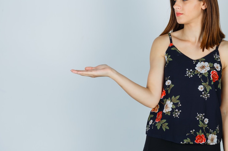 Foto gratuito señora atractiva en blusa fingiendo mostrar algo y mirando confiada, vista frontal.