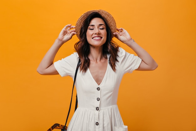 Señora atractiva en elegante sombrero sonriendo sinceramente sobre fondo aislado