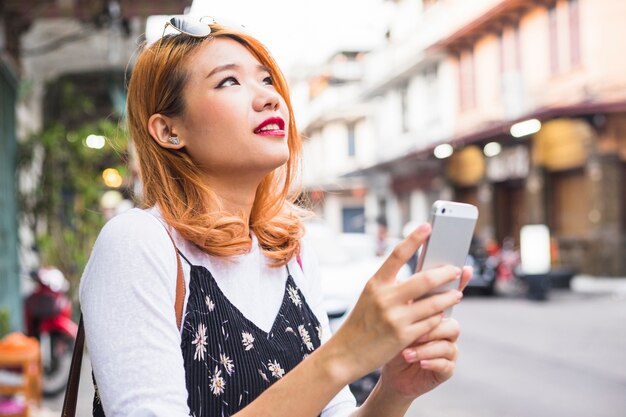 Señora atractiva con teléfono inteligente en la calle