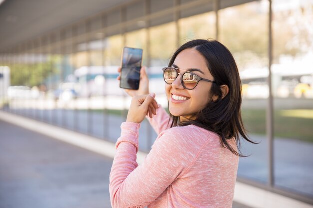 Señora bastante joven feliz que toma la foto del selfie al aire libre