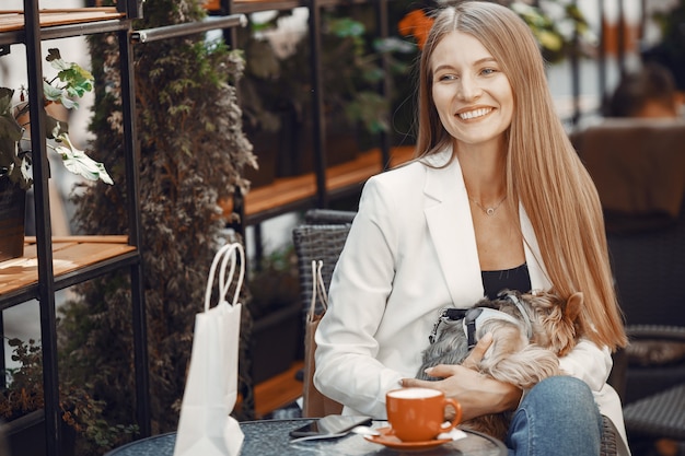 Señora bebe un café. Mujer sentada a la mesa. Chica con un lindo perro.