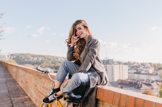 Señora bien vestida de buen humor posando juguetonamente en el fondo de la ciudad en un clima cálido