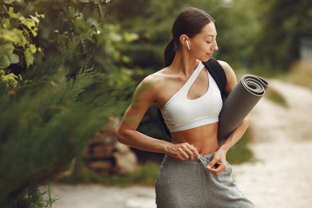 Señora bonita en un parque. Morena se prepara para el yoga. Chica en traje deportivo.