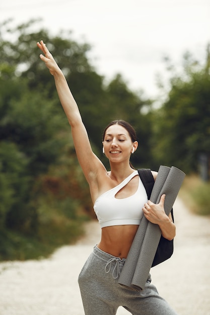 Foto gratuita señora bonita en un parque. morena se prepara para el yoga. chica en traje deportivo.