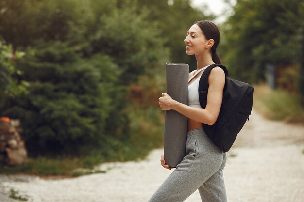 Señora bonita en un parque. Morena se prepara para el yoga. Chica en traje deportivo.