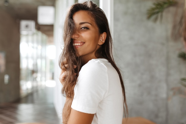 Señora bronceada con maquillaje natural está sonriendo afablemente