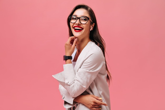 Señora de buen humor riendo sobre fondo rosa. Linda mujer de pelo largo con hermosa sonrisa en reloj negro mira a la cámara.