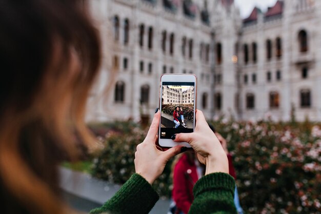 Señora de cabello oscuro que usa el teléfono para la foto de su amiga