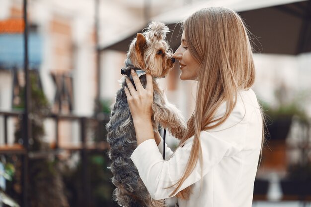 Señora en un café de verano. Mujer sentada a la mesa. Famale con un lindo perro.