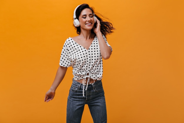 Foto gratuita señora en camiseta de lunares está disfrutando de la canción con auriculares