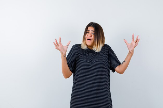 Señora en camiseta negra levantando las manos en gesto de perplejidad, vista frontal.