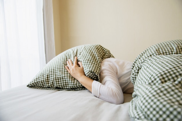 Foto gratuita la señora se cubre la cabeza con una almohada en la cama.