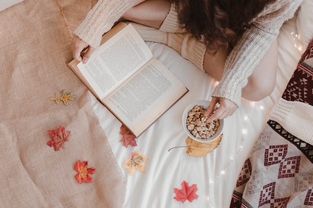 Señora de cultivos merienda y libro de lectura en la cama