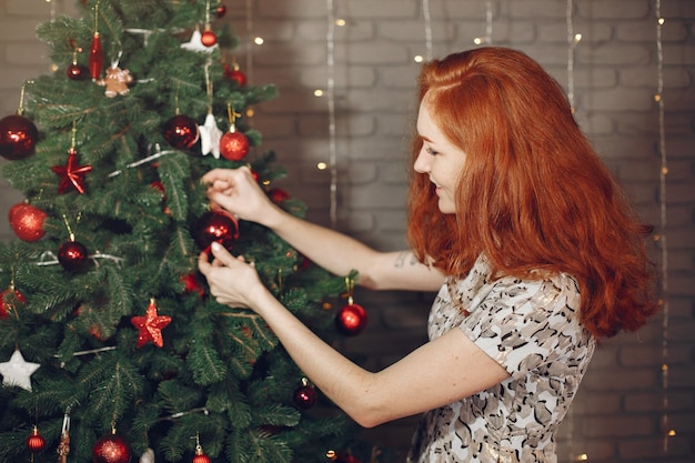 Señora elegante cerca del árbol de Navidad. Mujer en casa con champagne.